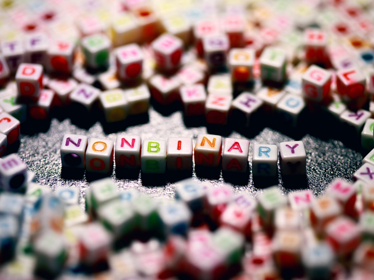 Small white cube-shaped beads with letters that spell out non-binary