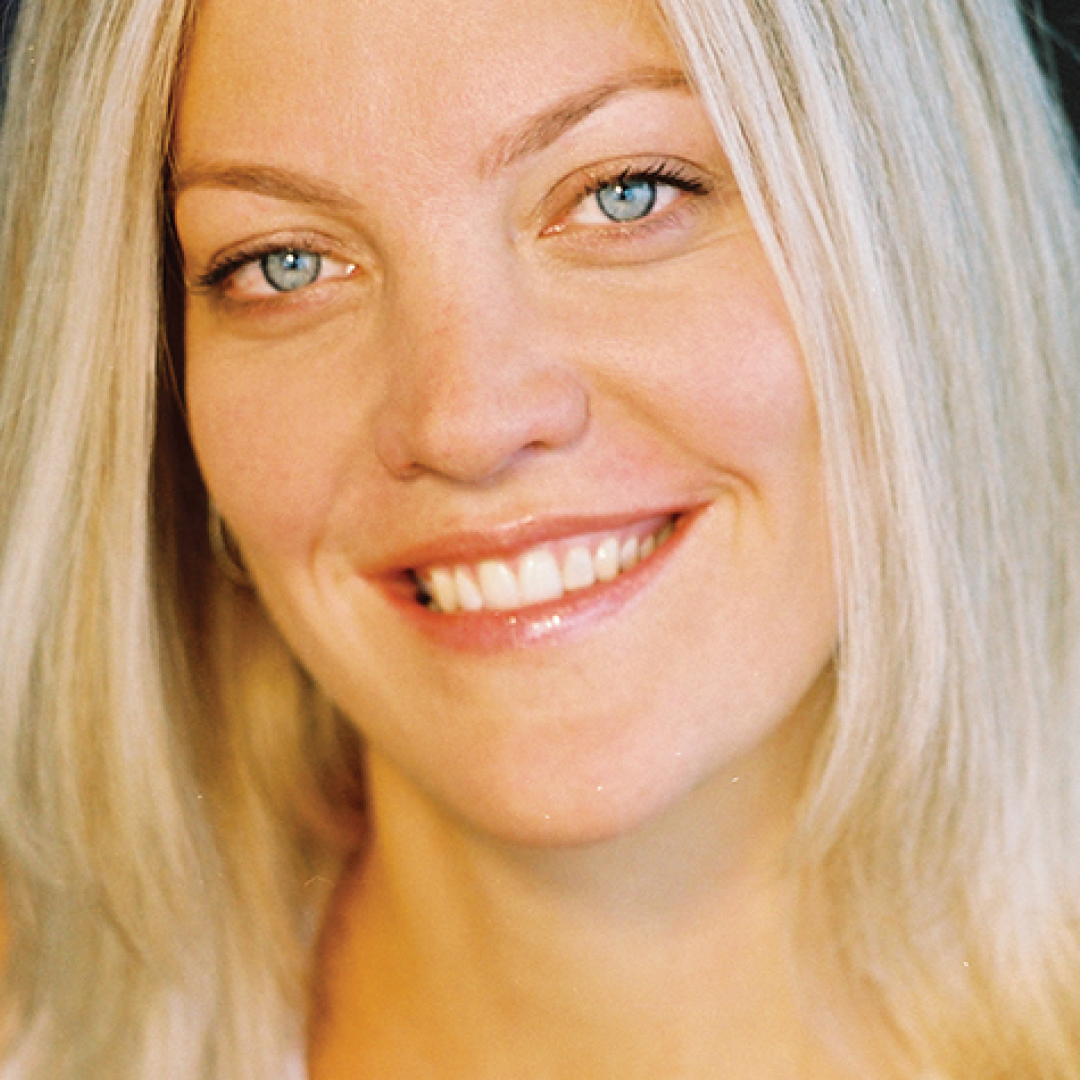 Close-up headshot of Jocelyn Hamilton smiling. She has long blonde hair and is wearing a dark top.