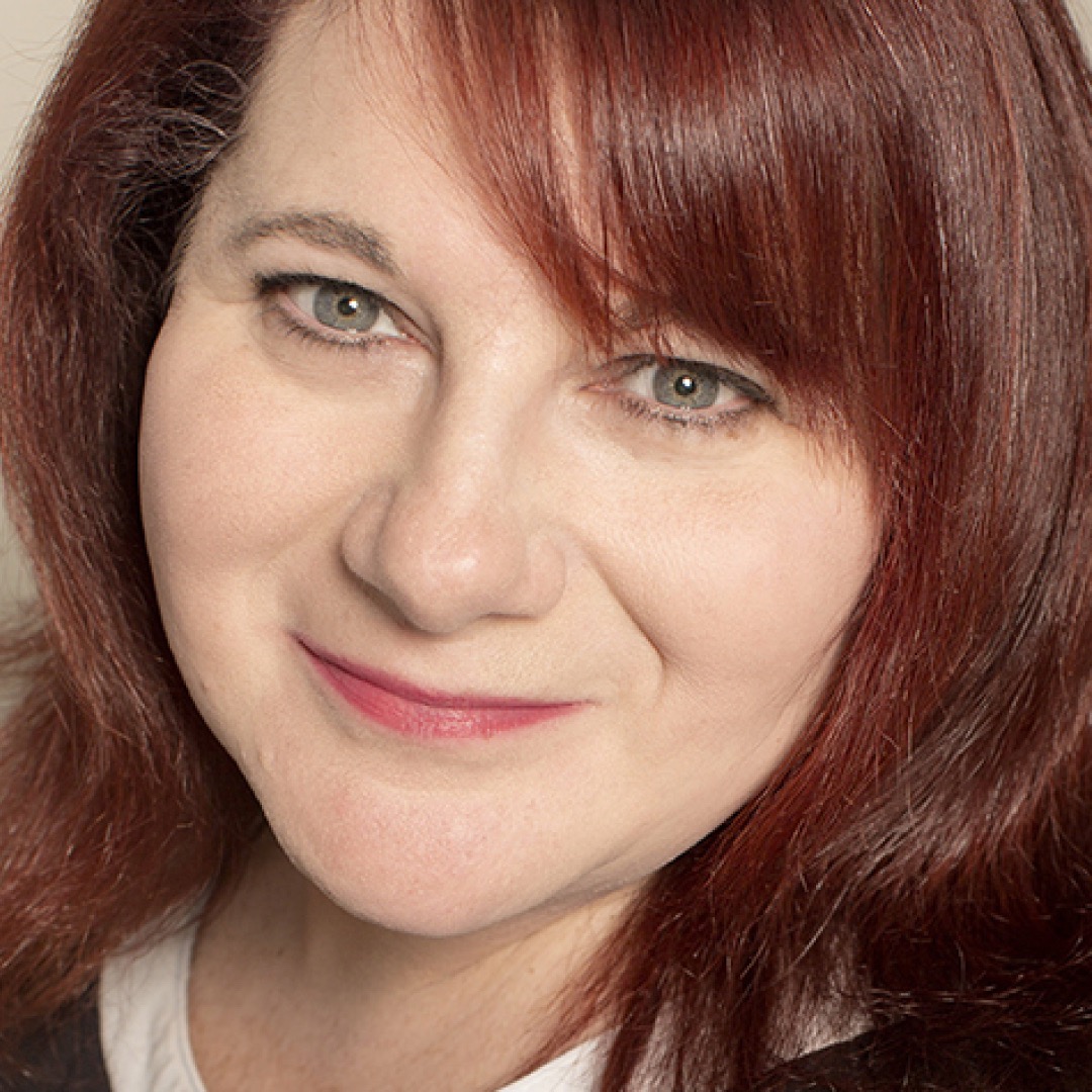 A close-up headshot of Melissa R. Byer. She has long light brown hair and is smiling. She is wearing a dark top.