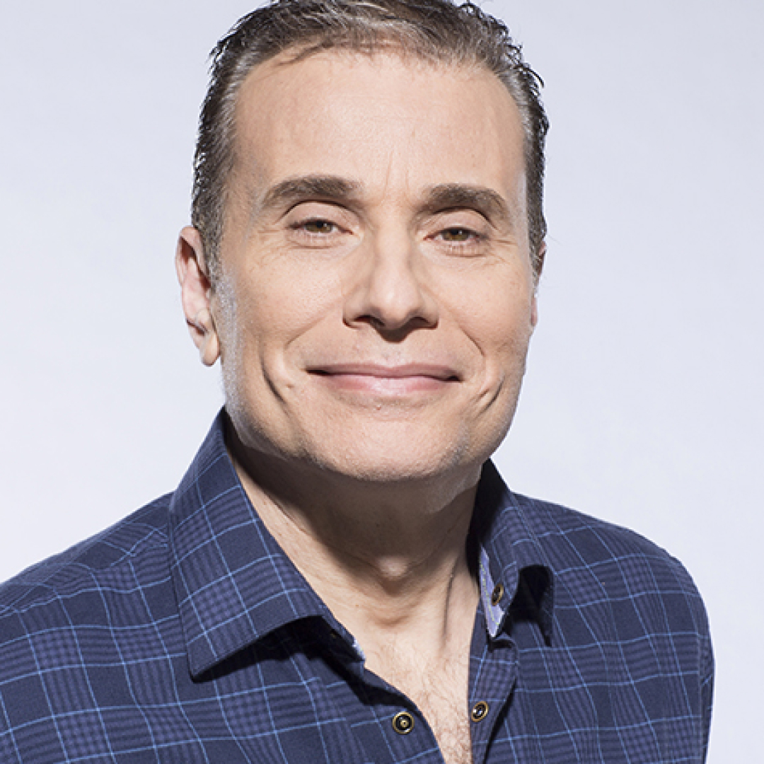 A close-up headshot of Michael Landsberg, with short dark hair, wearing a dark blue checkered shirt.