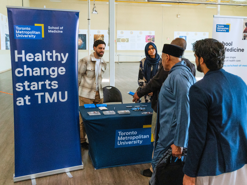 Outreach table at Sayeda Khadija Centre mosque in Mississauga with TMU students providing health system information.