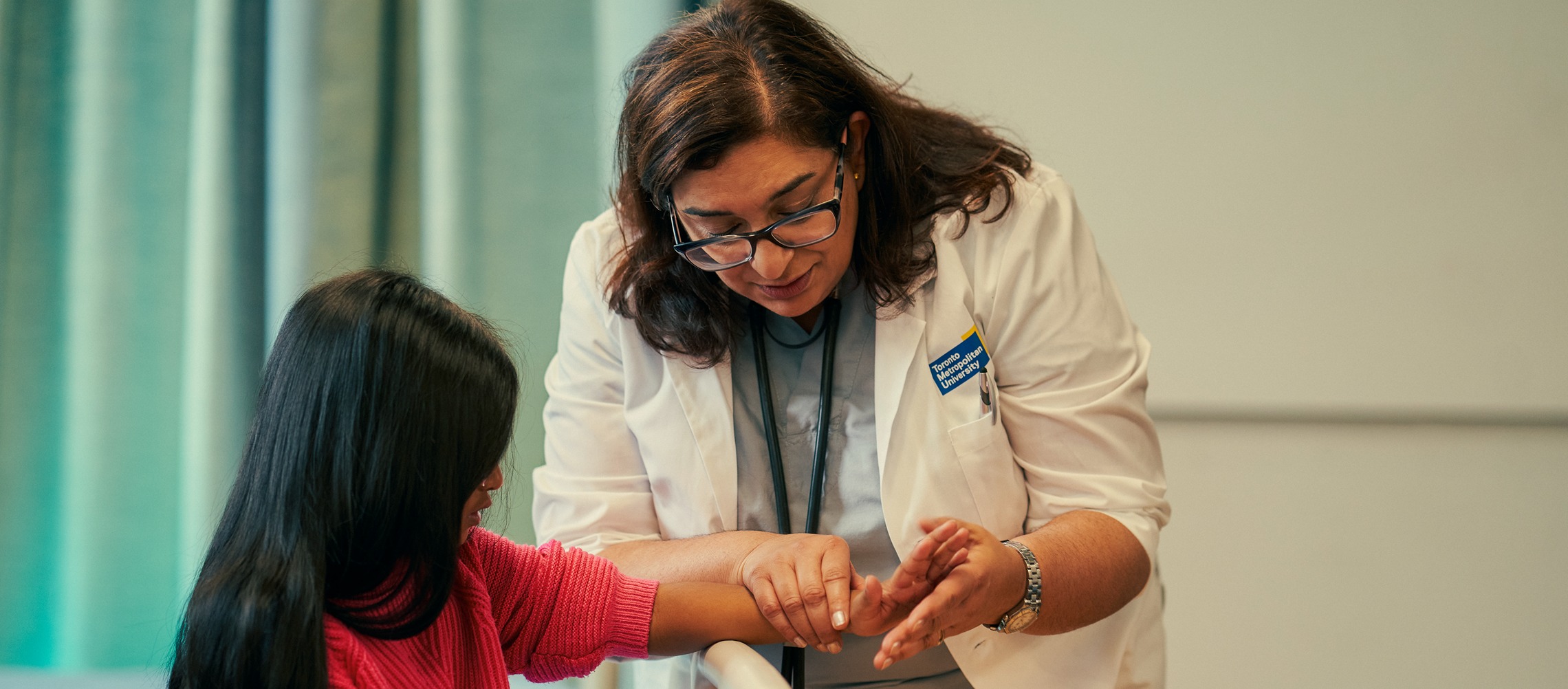 An Indigenous female doctor stands in a busy hospital ward