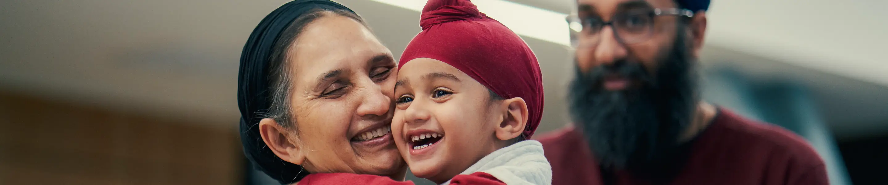 parents and a boy wearing a turban smiling together