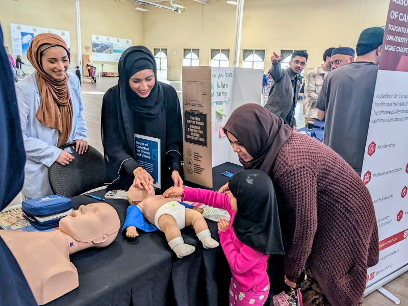 MD students supervise a child learning CPR on a resuscitation mannequin at the Sayeda Khadija Centre mosque in Mississauga. 
