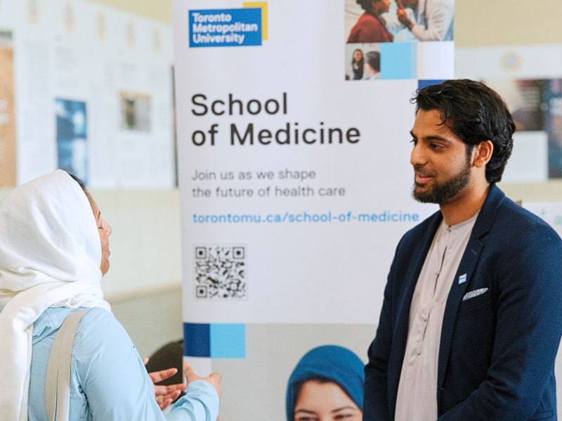 First-year TMU medical student Nabeel Mansuri speaking with a woman at a community health outreach event inside a Mississauga mosque.