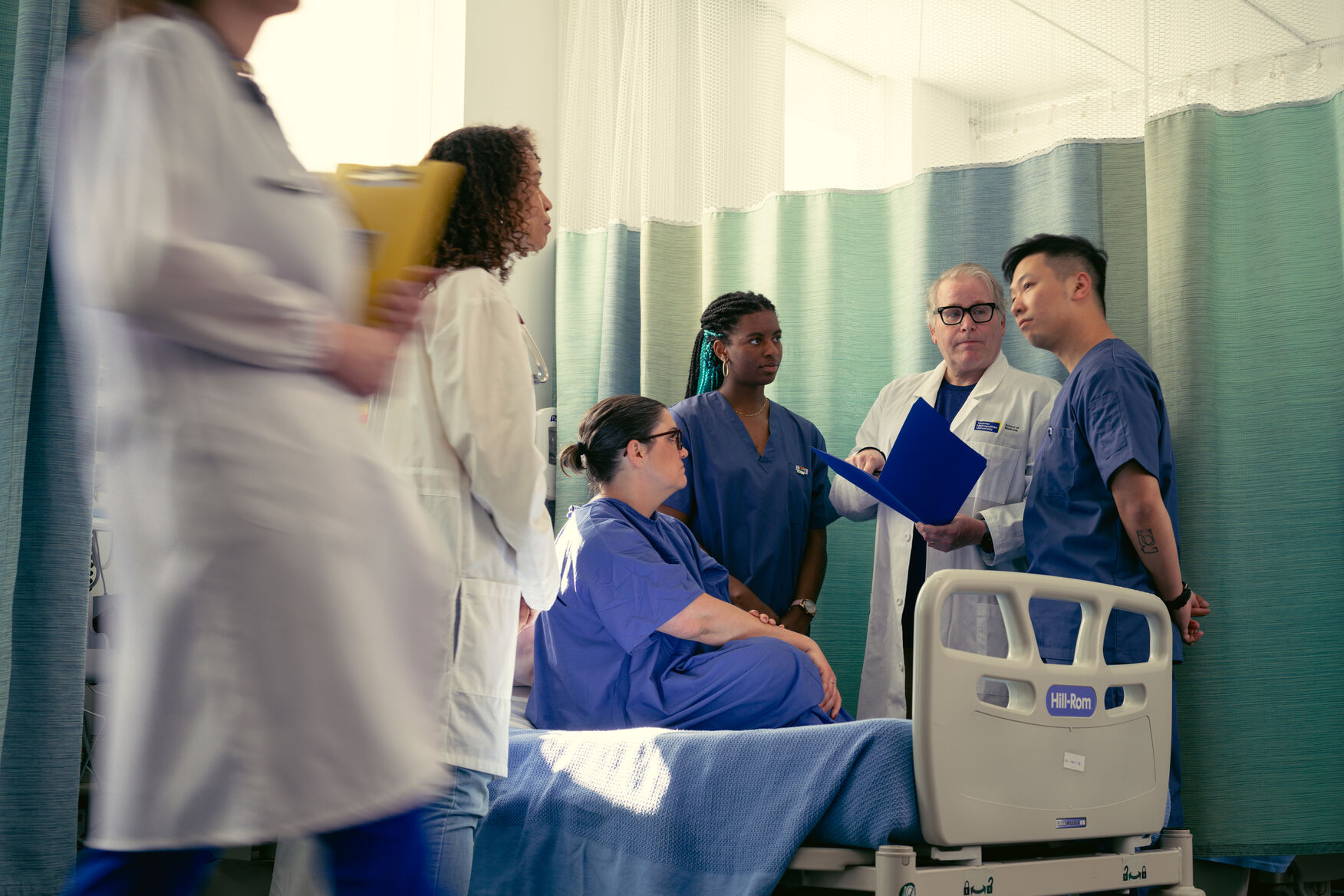 A small group of physicians gathered at the patients bedside discussing their case. 