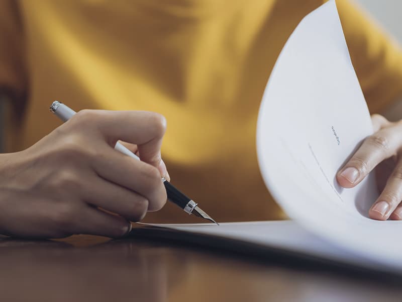 A female hand signing papers with a fountain pen in right hand