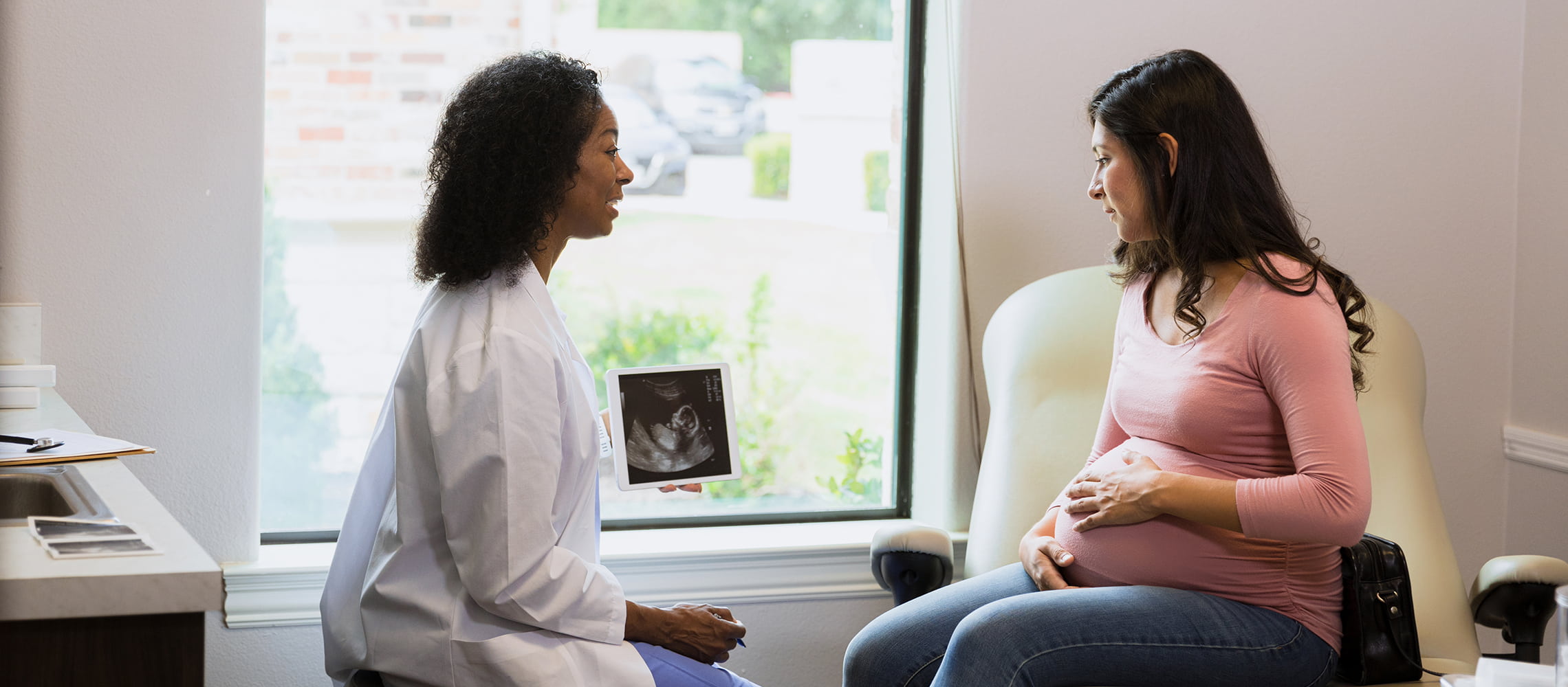 Healthcare provider speaking with a pregnant patient during a prenatal appointment.