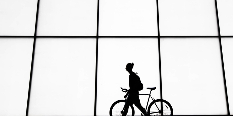 Figure with bicycle in front of white building
