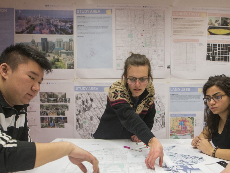 Planning students gather around a table with blueprints