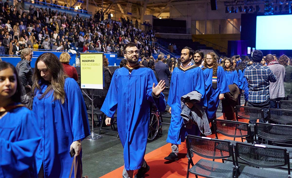 Students walking at convocation, one student waving.