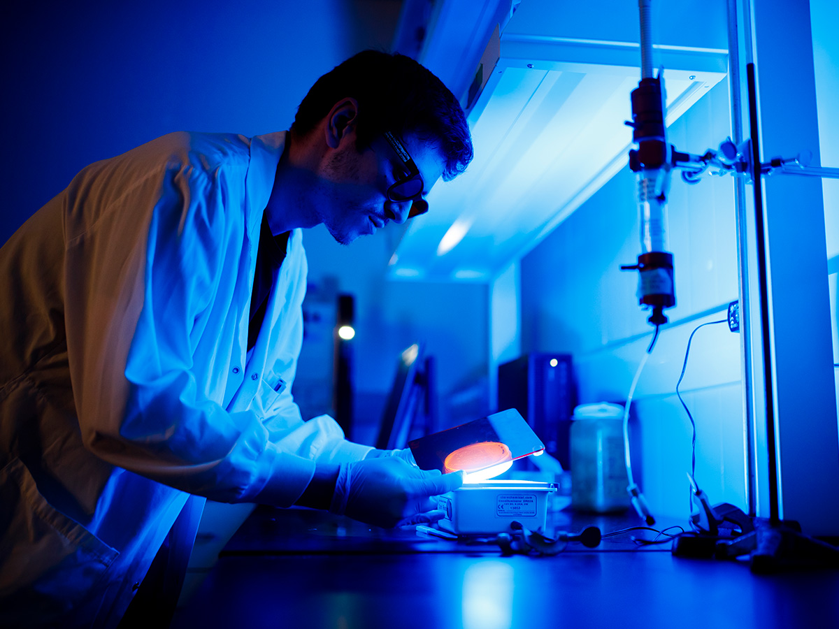 Biomedical sciences student in blue-lit lab conducting an experiment