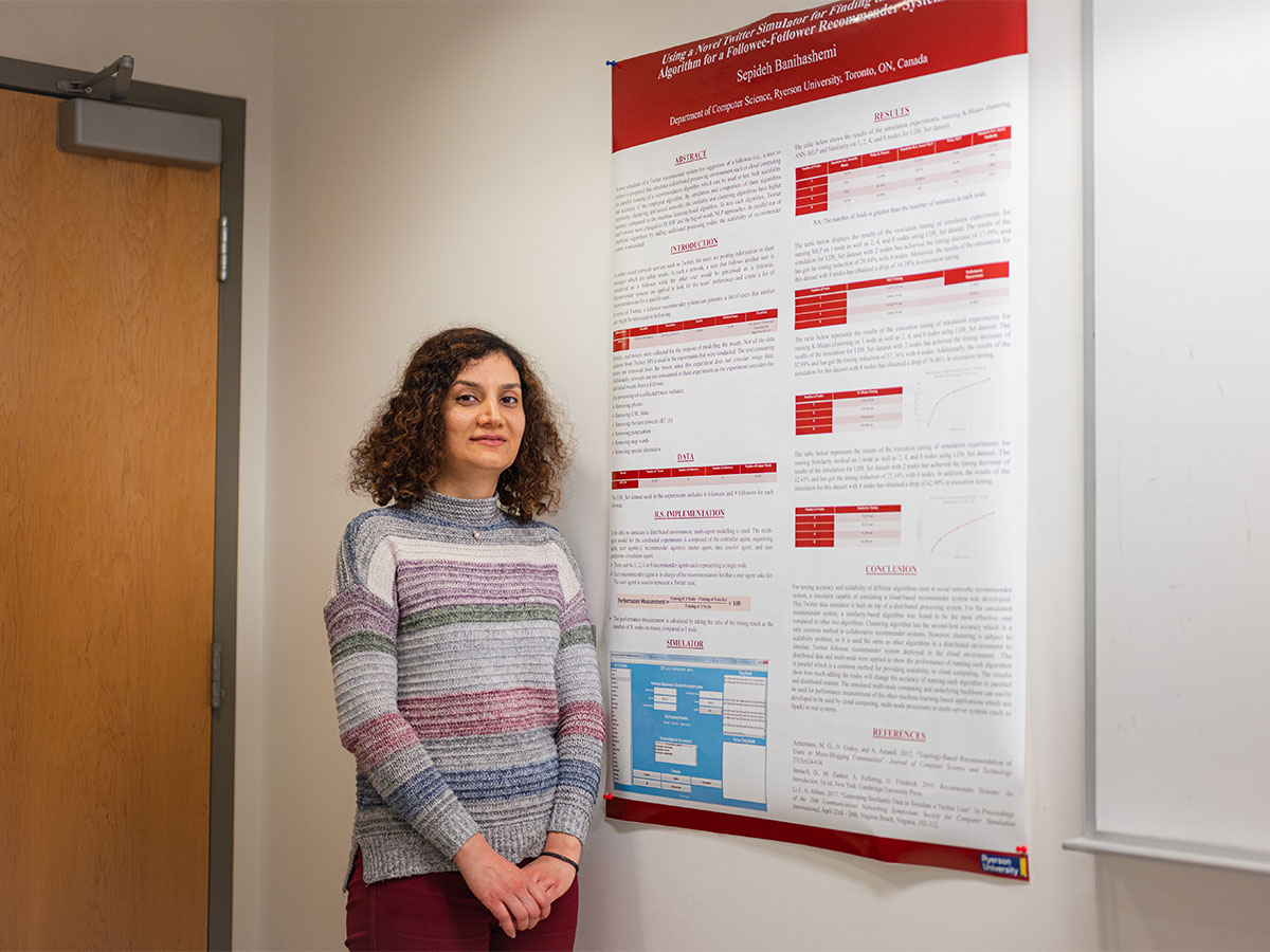 Sepideh Banihashemi standing beside her research poster
