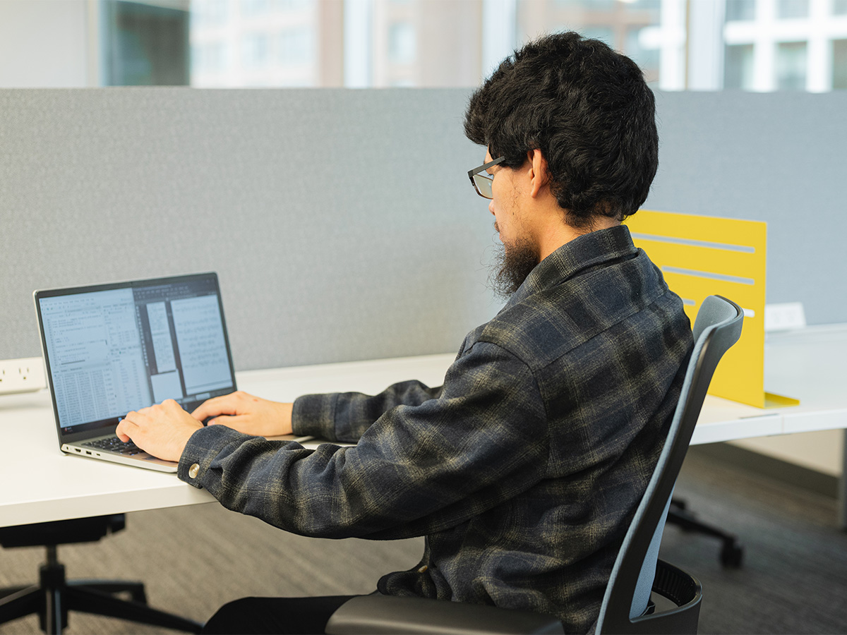Samuel Reano sitting at a workstation with his laptop open