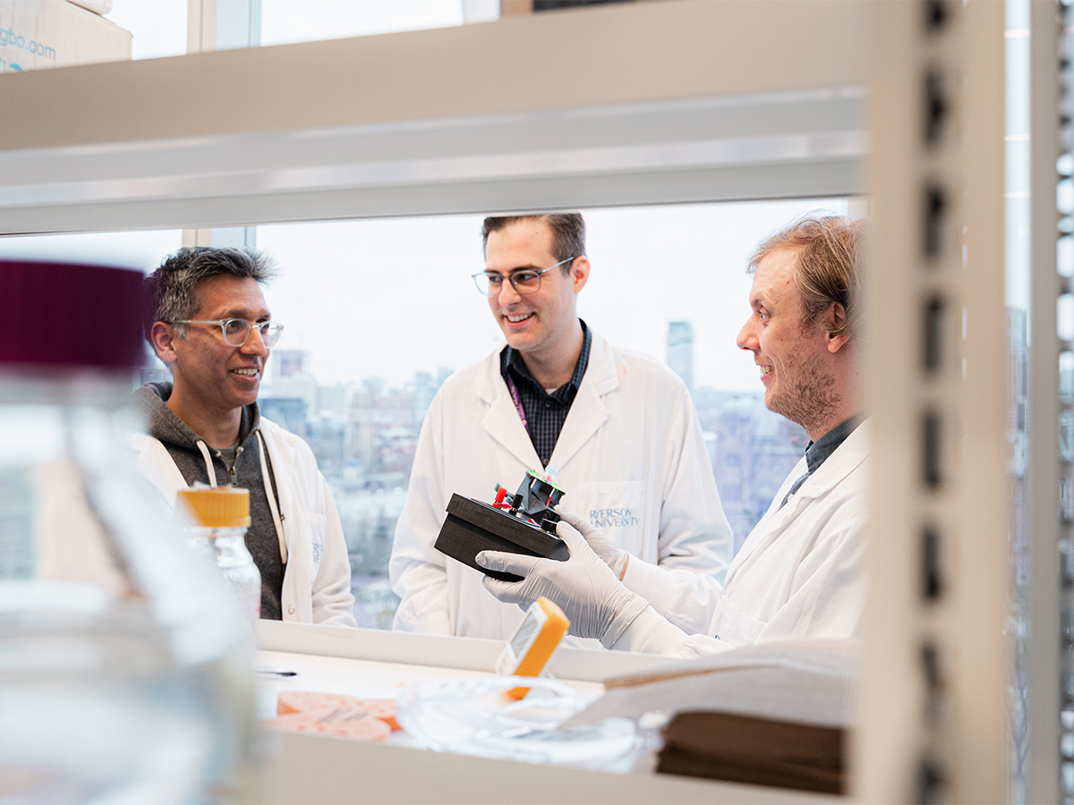 Thomas Nesmith and his supervisors collaborating in a lab, while holding the OpenPore device.