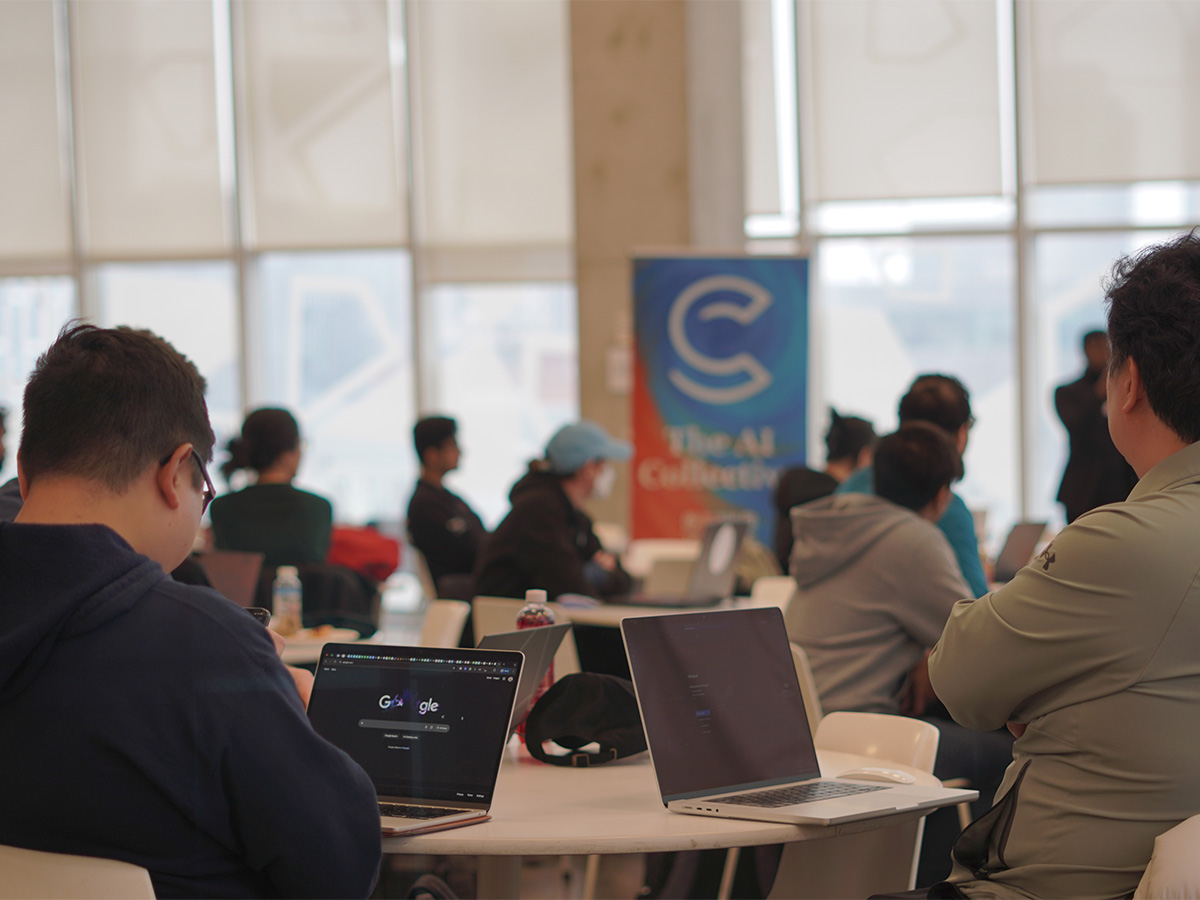Two students with their laptops open at a talk by The AI Collective at TMU Tech Week