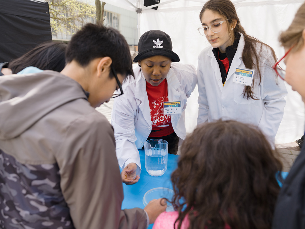 Two SciXchange volunteers conduct a science demonstration for a family at Science Rendezvous
