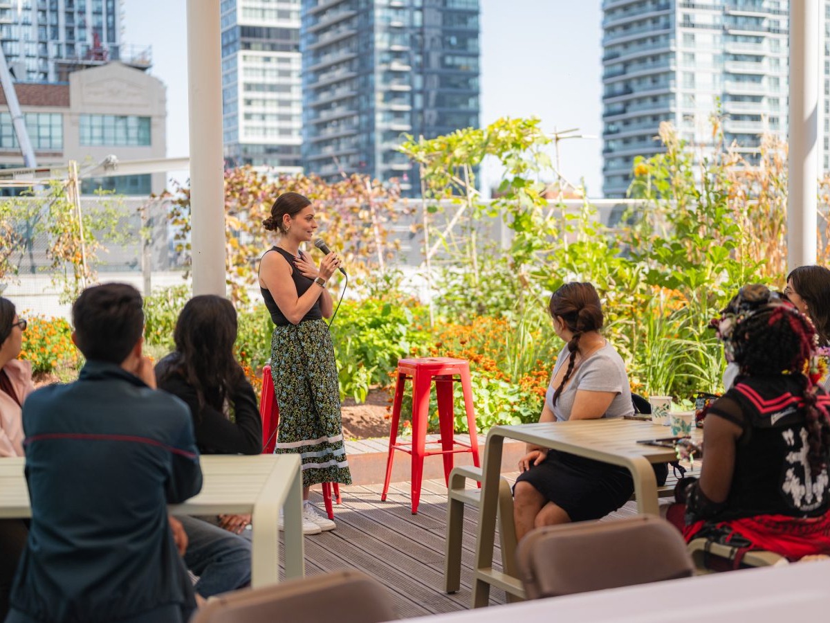 Group of students sitting down watch speaker Sommerly Grimaldi-Ertl talk in the rooftop garden