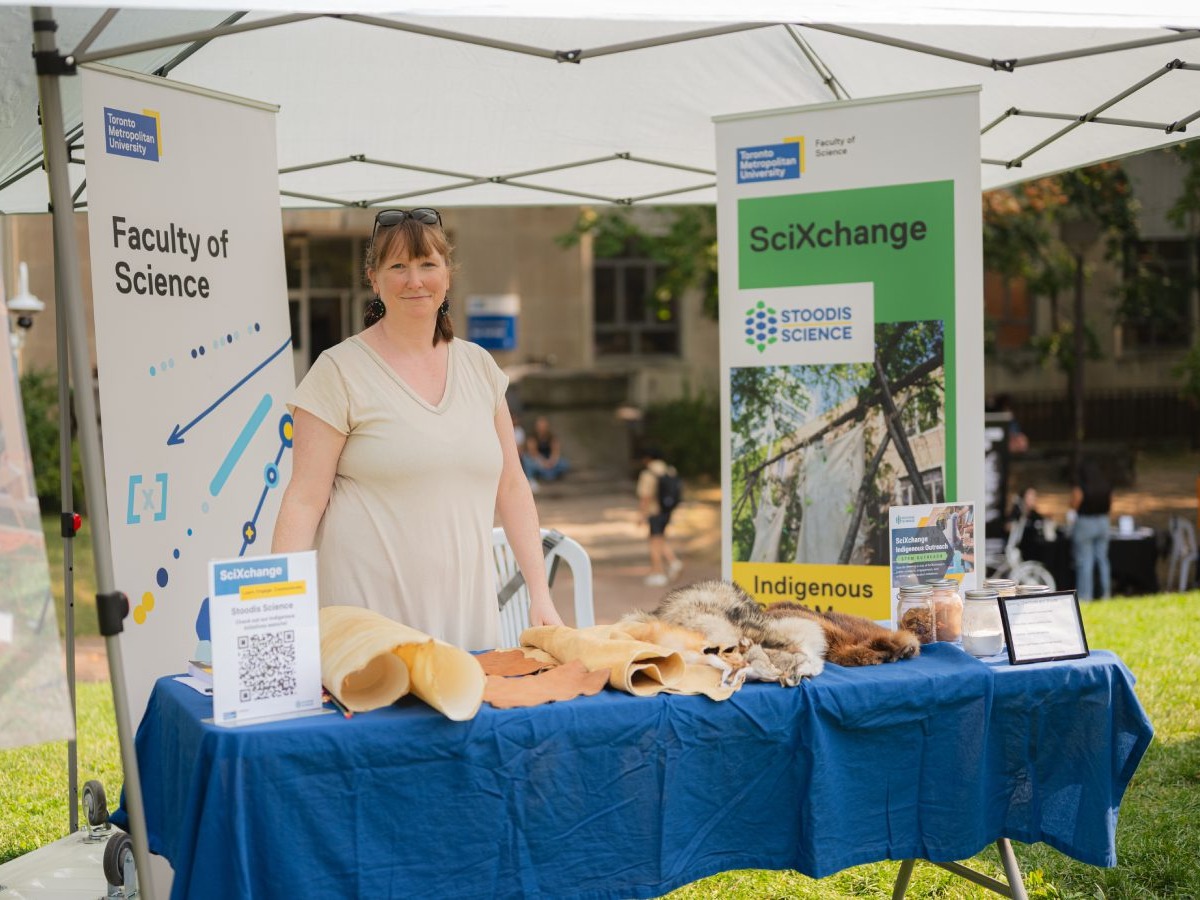 Leigh Paulseth standing at a Faculty of Science stand at the SciXchange event. Various hides are displayed on the table