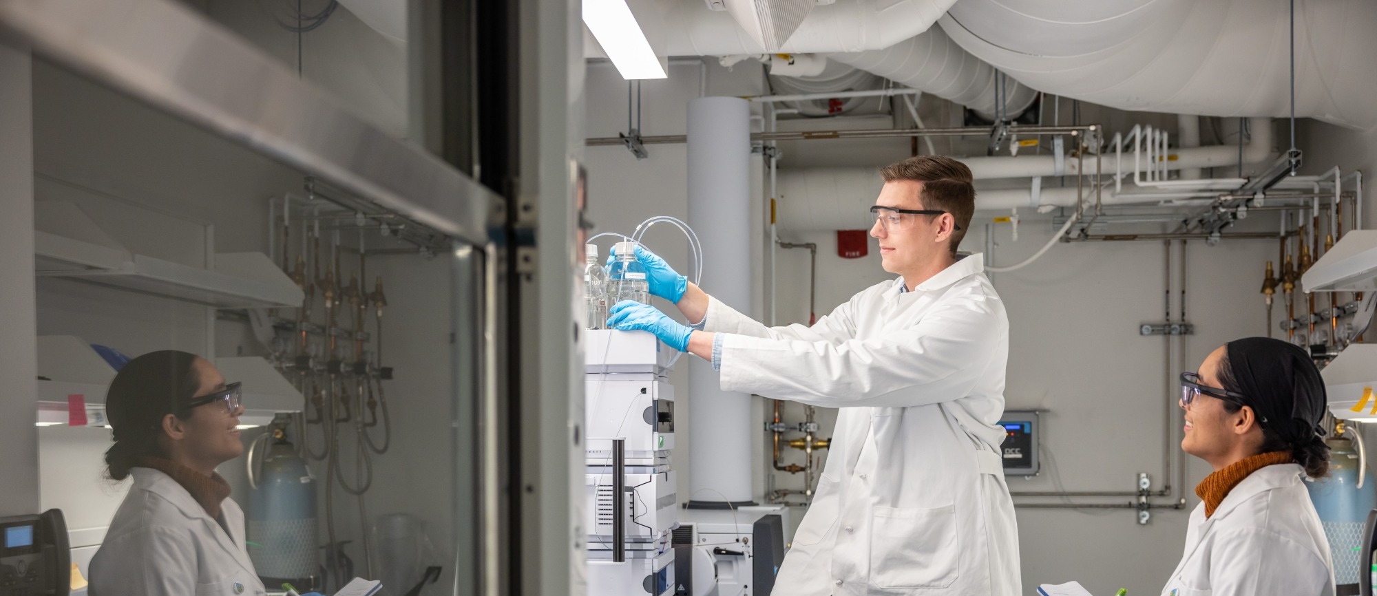 Two students in lab attire working in a lab
