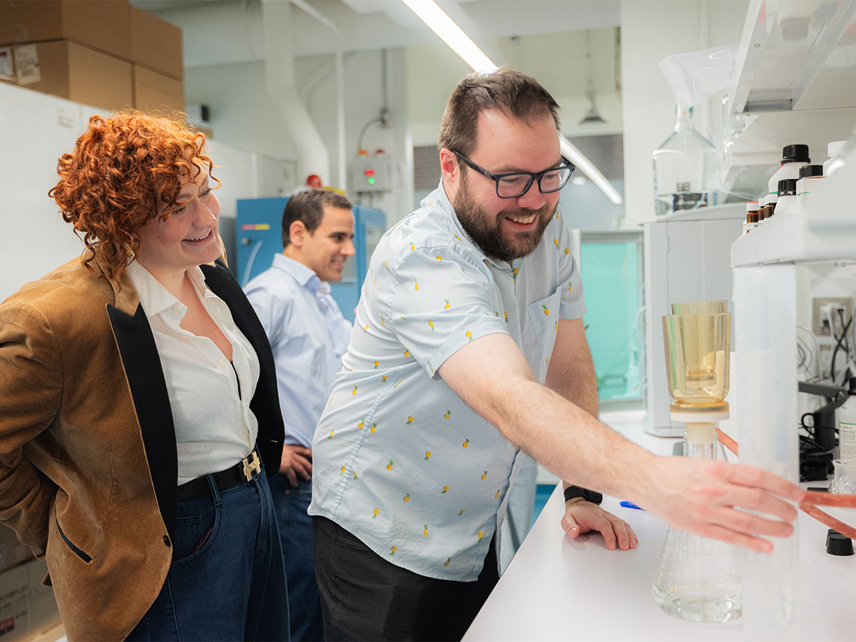 Jet Ice researcher reaches for a cylinder while collaborating in a lab