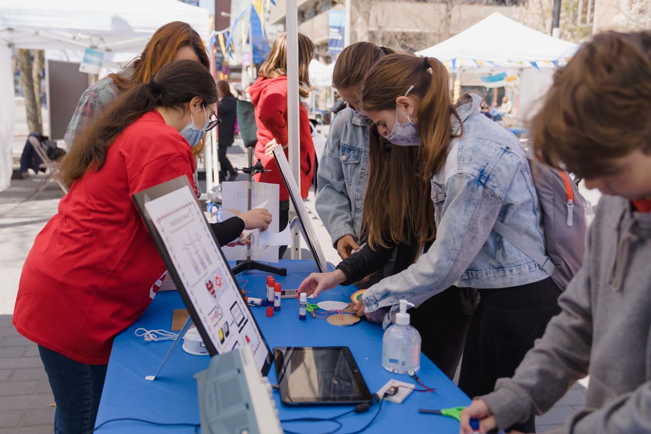 Four participants making spinning whirligigs at a booth.