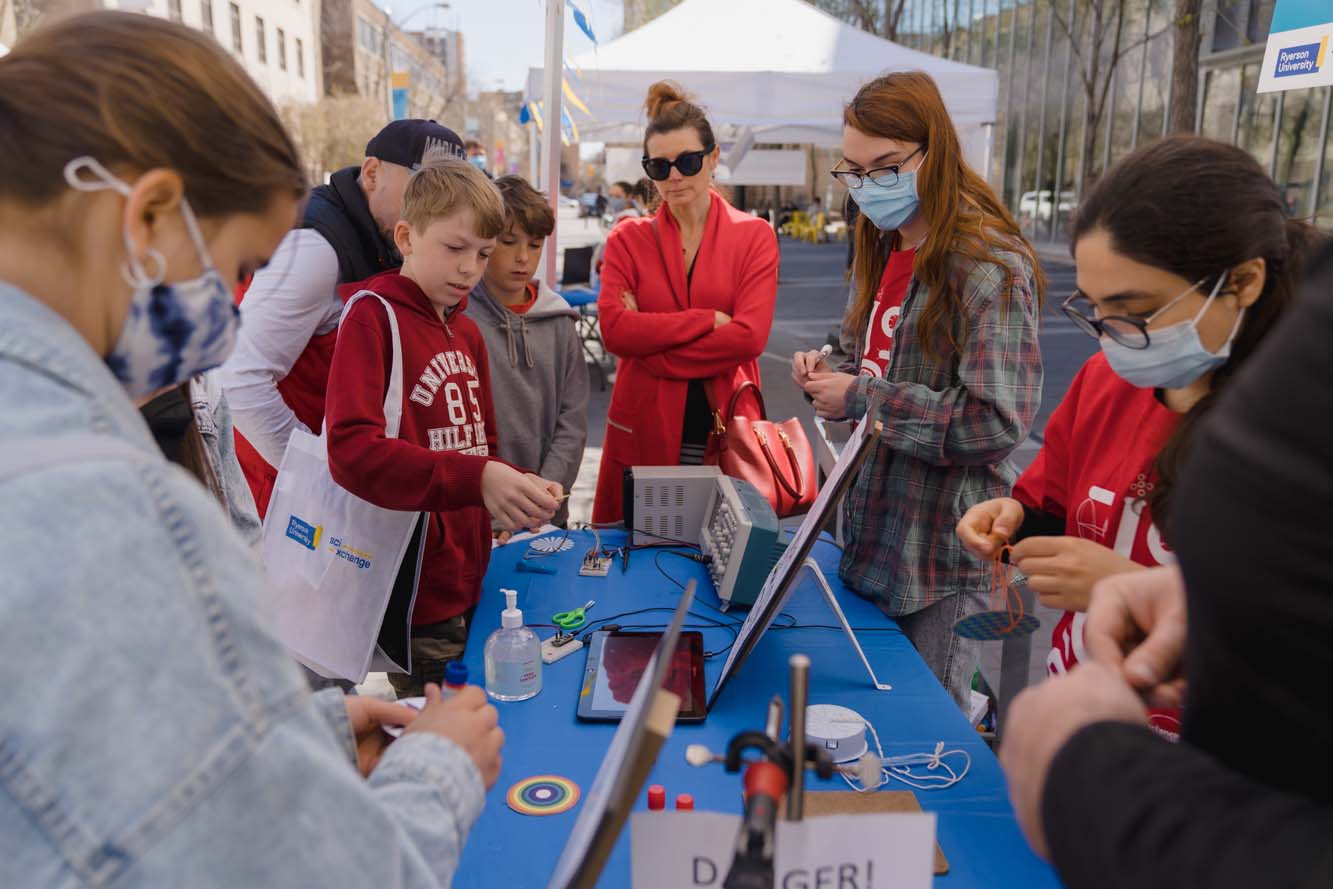 A group of participants making spinning whirligigs with the volunteer at a booth.