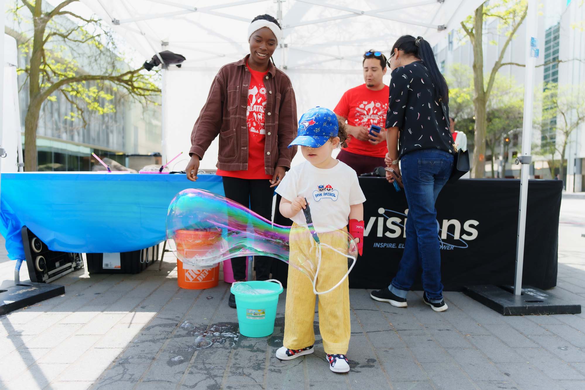 A child making a big bubble with a volunteer at the Visions of Science booth.