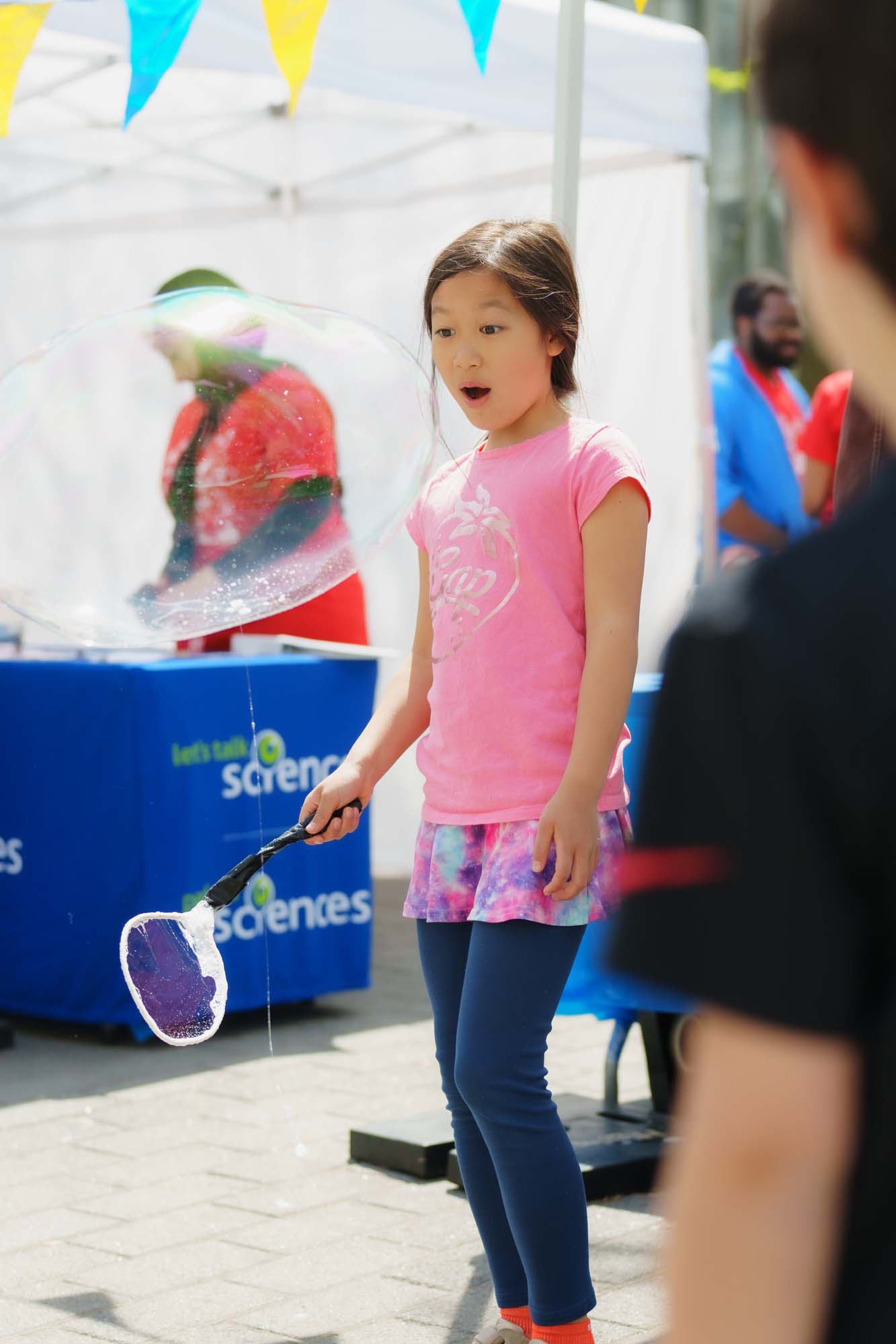 A child is amazed by the size of the big bubble she just made.