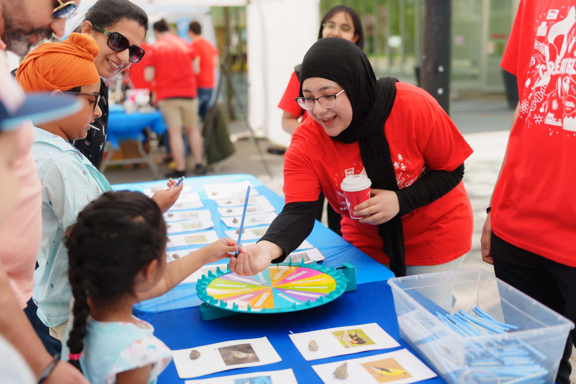A volunteer giving a blue pencil to a child after playing the bird identification activity at the booth.