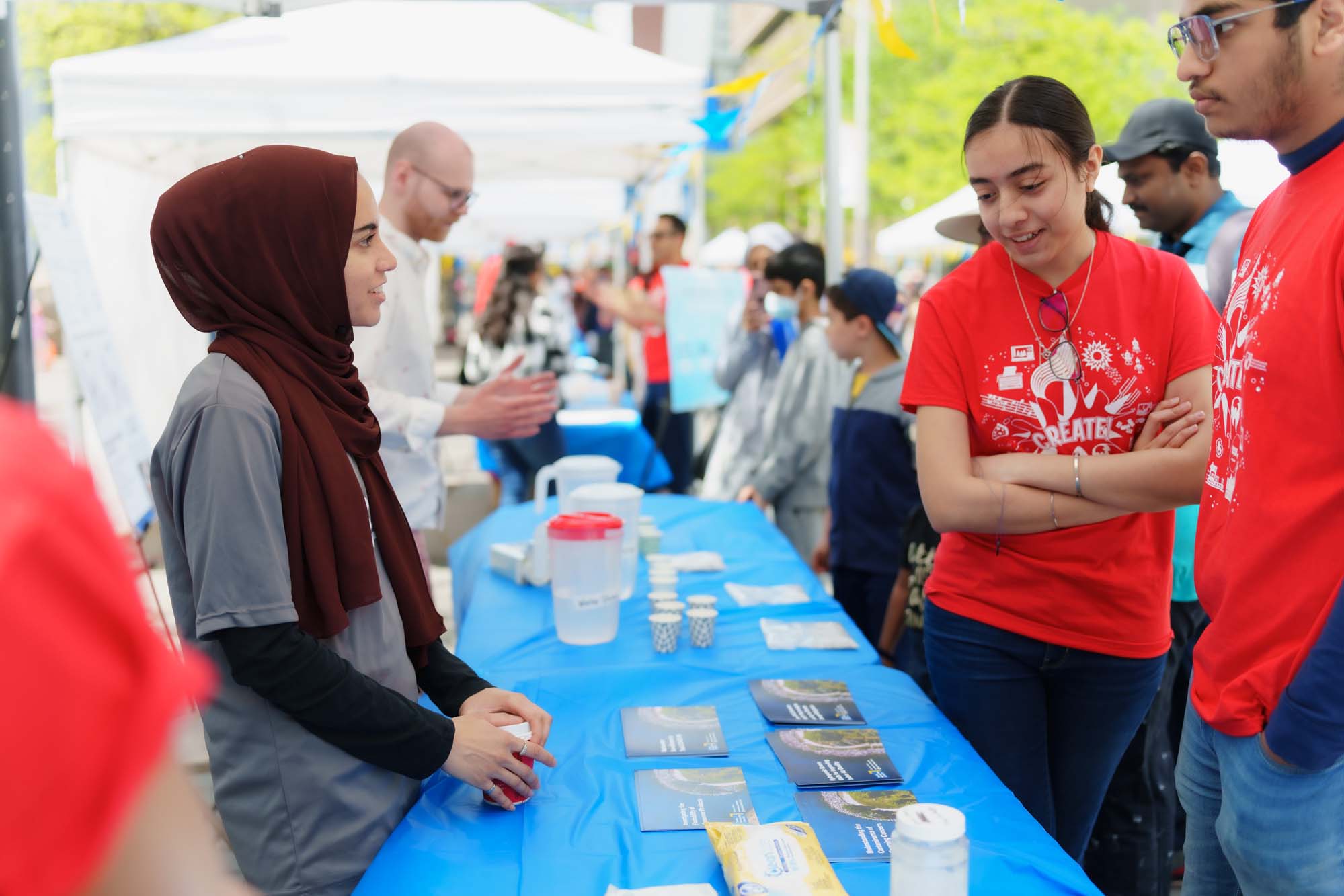 A volunteer talking to two participants at the TMU Urban Water booth.