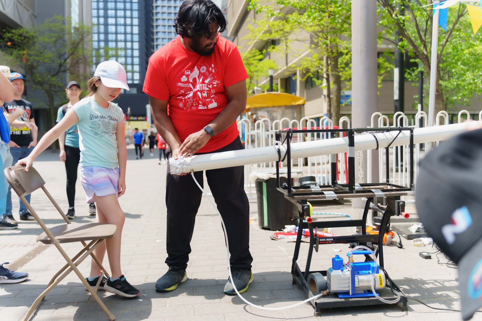 A Science Everywhere volunteer setting up the vacuum launcher in front of a child.
