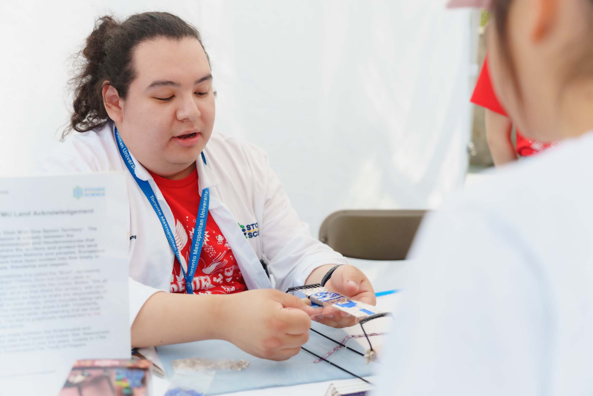 Indigenous science outreach coordinator Caleb Wesley is demonstrating the Indigenous loom beading at the Land Acknowledgement booth.