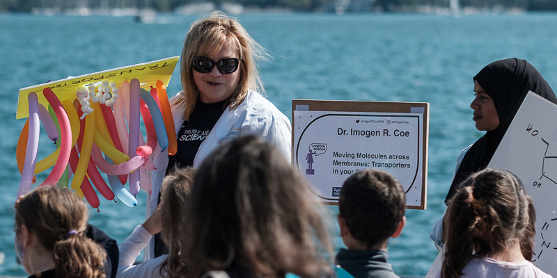 Dr. Imogen Coe with balloon display, participants and volunteer looking at her