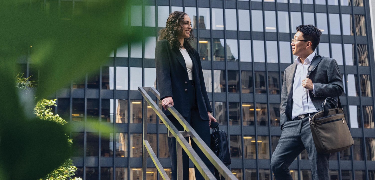 man in suit with briefcase speaking to women in suit on staircase