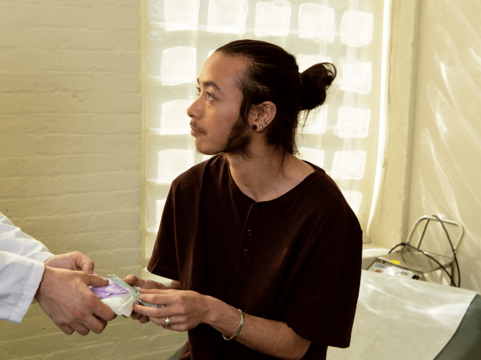 A genderqueer person receiving products from a doctor