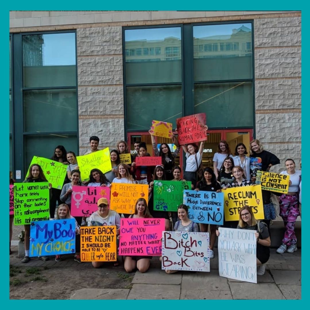 A group of students holding bight coloured posters.