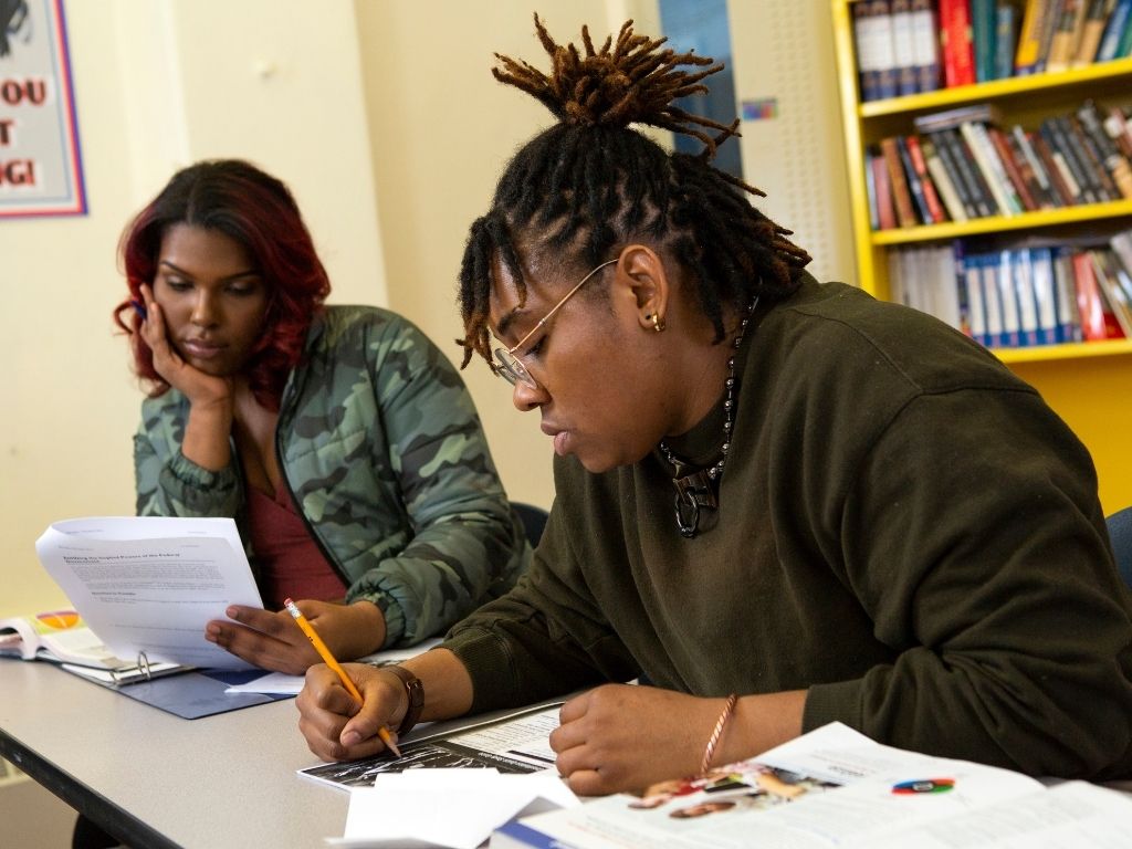 A non-binary student taking notes in class