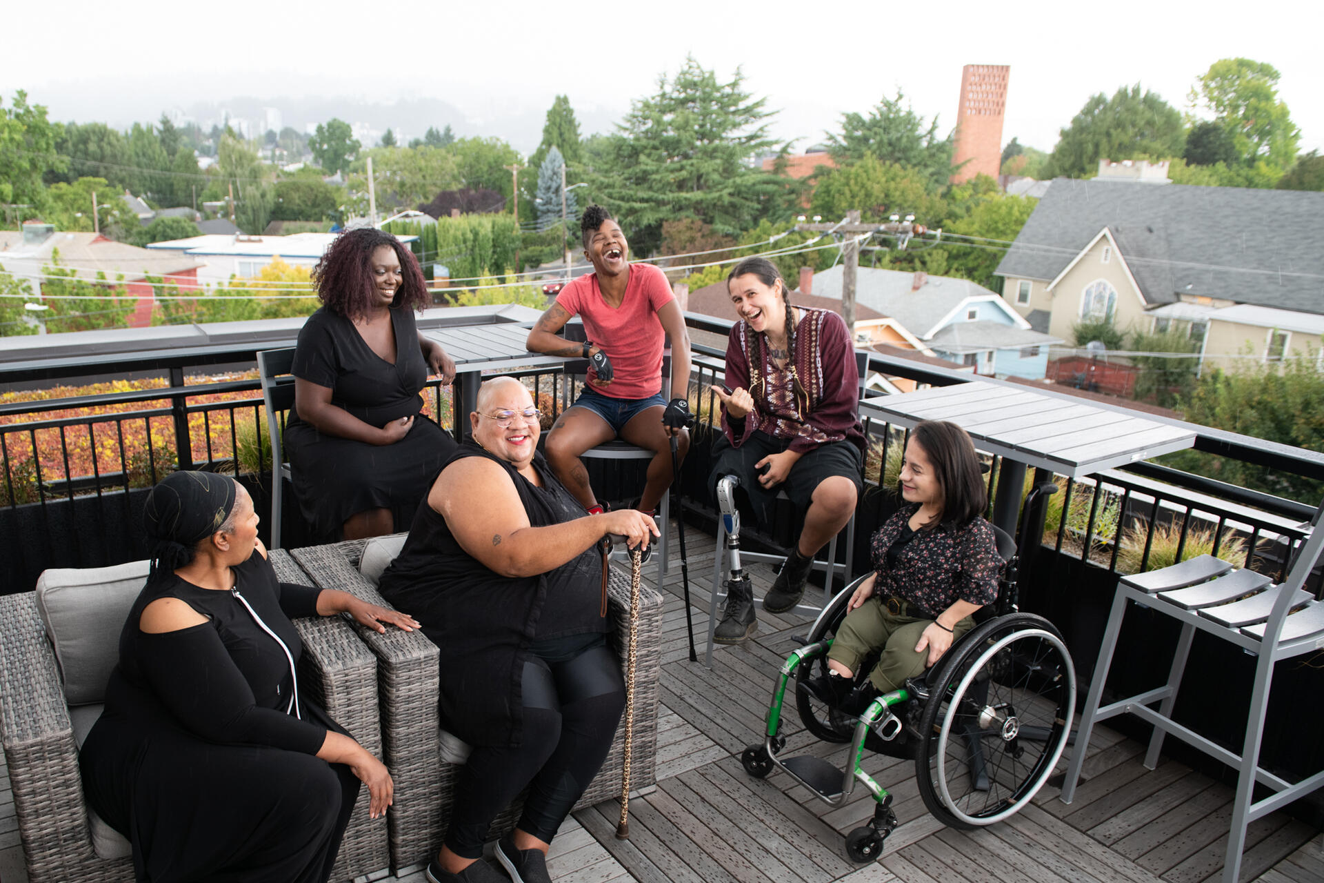 A group of women smiling and talking in an outside setting.