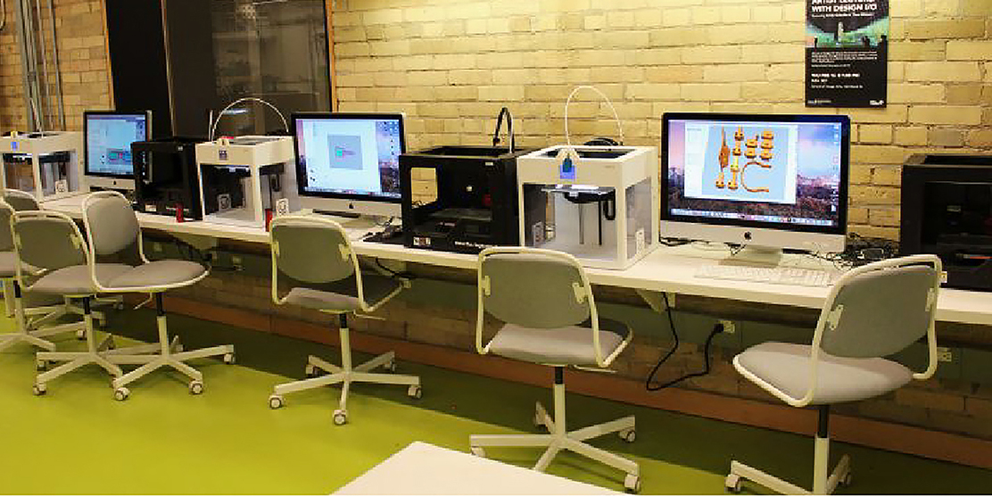 Chairs front of iMacs with exposed brick wall