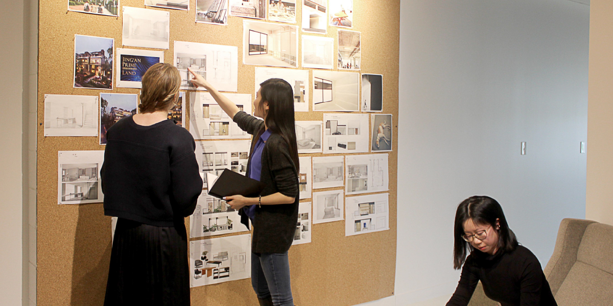 Students pointing at a board with sketches pinned to it