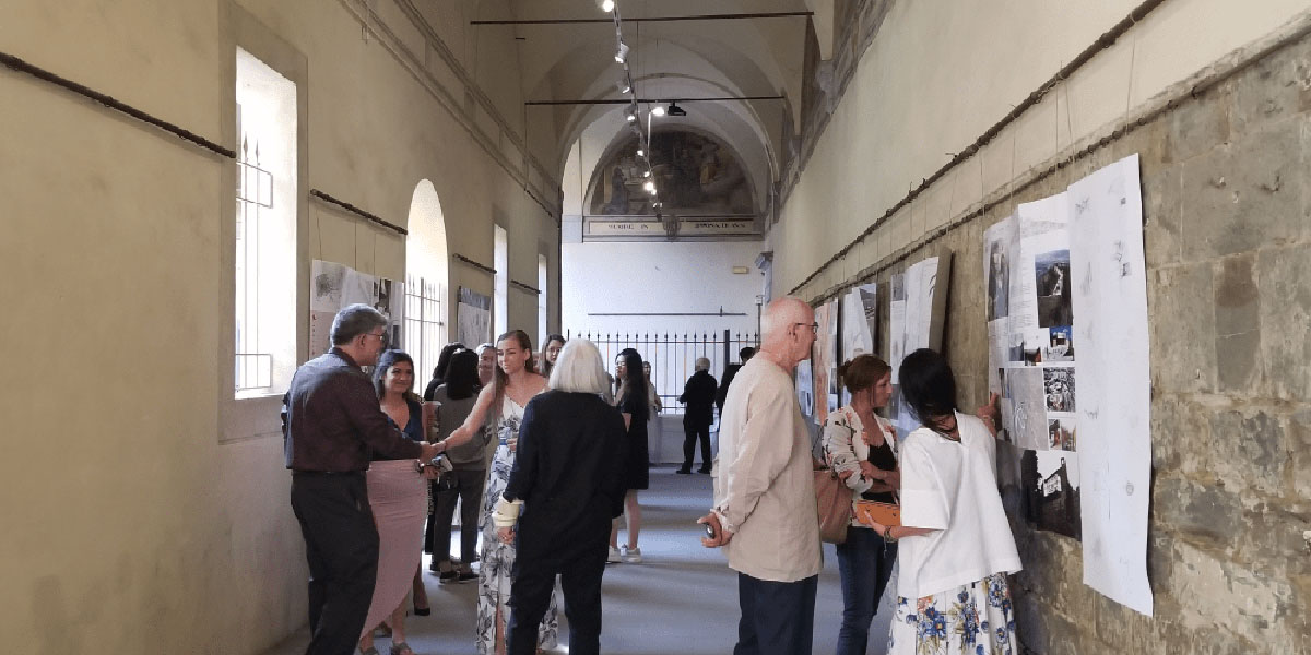 students and faculty inside a hallway conversing and examining student projects in Italy