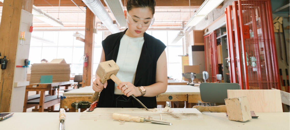 Student in the workshop using chisel on woodworking project 