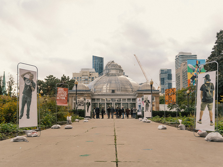 Pathway up to Allan Gardens conservatory with large banners of historical figures.