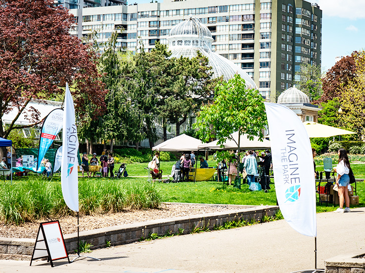 Sunny day at Allan Gardens park with white tents and booths on the lawn.