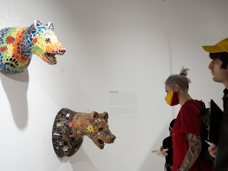 Two people looking at mosaic bear head installations by artist Michel Dumont.