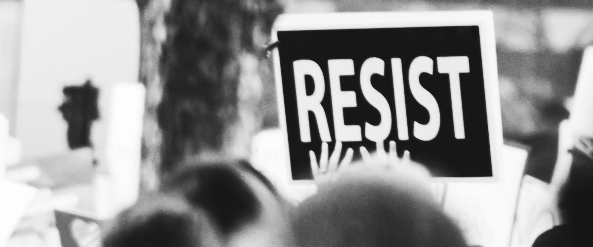a person holding a 'resist' sign at a protest
