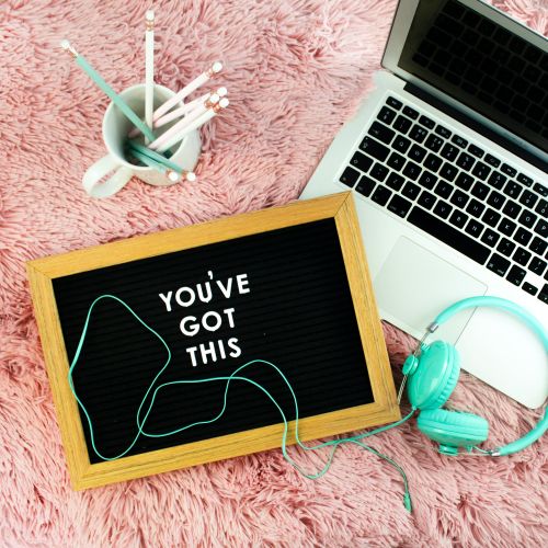 a lettered sign reading 'You've got this' lying by an open laptop computer and a pair of headphones