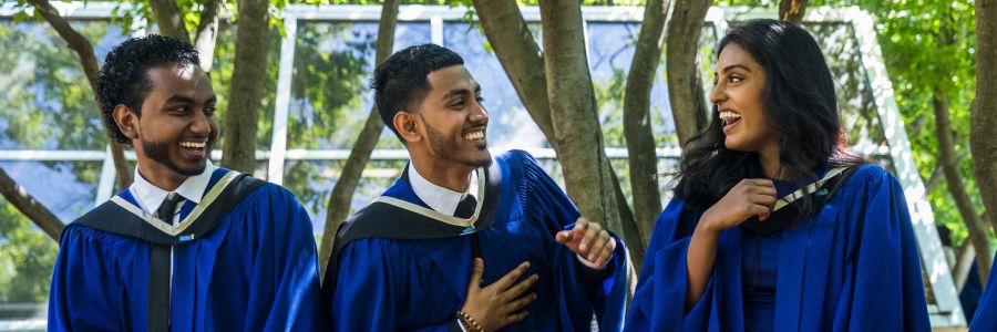 three students laughing and smiling in their convocation gowns