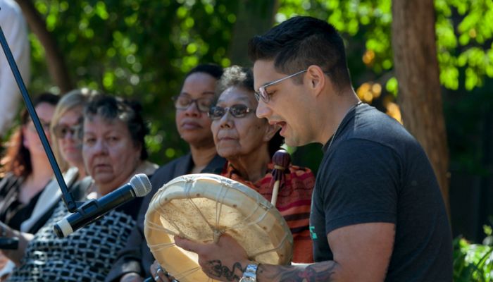 a student drums, while elders look on